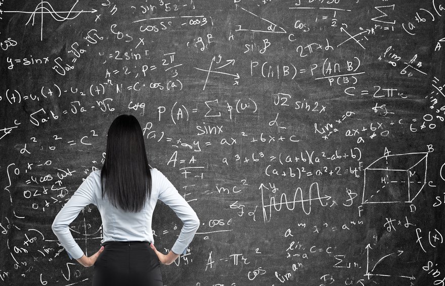 Person with hands on hips and looking at a blackboard full of math formulas.