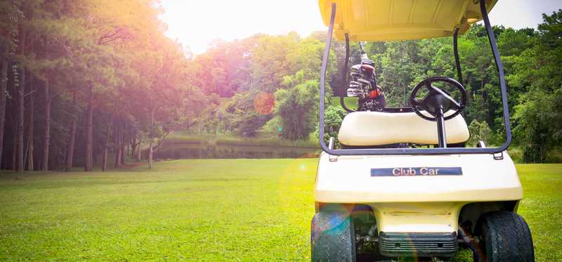 A golf cart sitting on a green course.