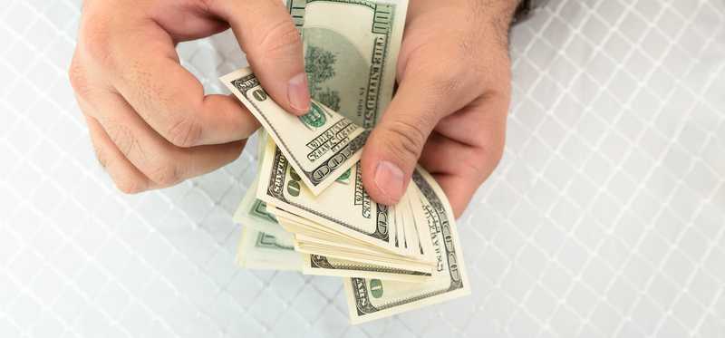 Hand peeling off bills from a stack.