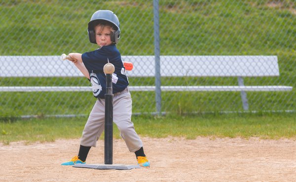 A small child hitting a baseball off of a tee.