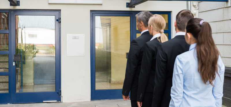 A line of people standing in front of a building labeled Job Center.