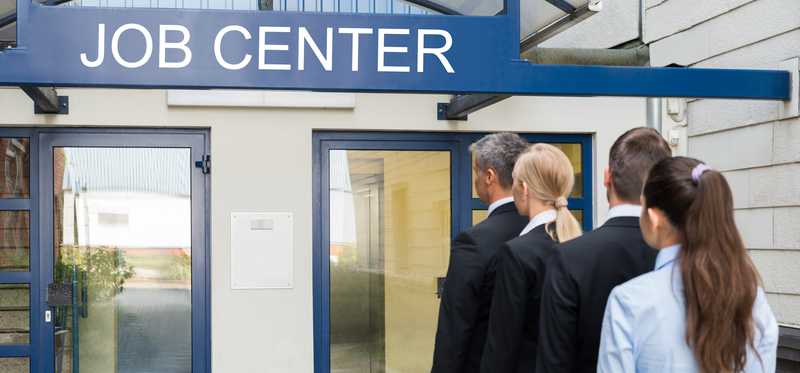 A line of people standing in front of a building labeled Job Center