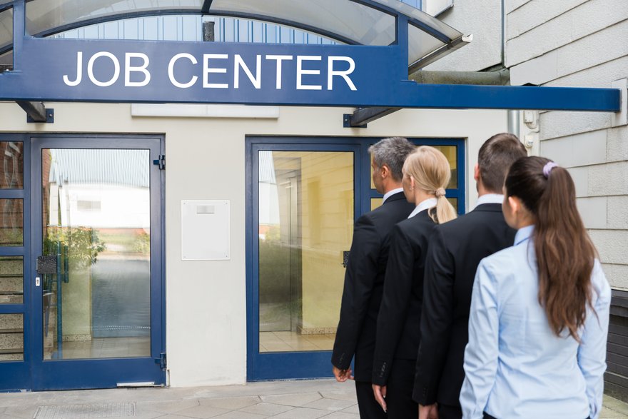 A line of people standing in front of a building labeled Job Center.
