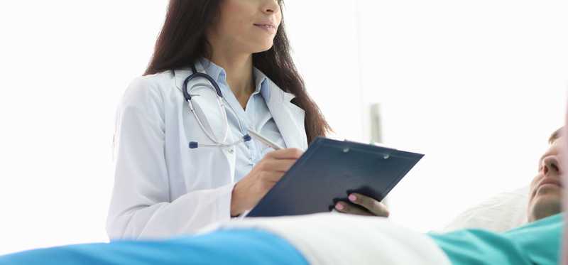 A doctor standing over a patient in a bed.