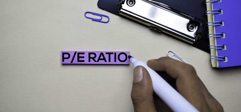 A hand writing the words PE Ratio.
