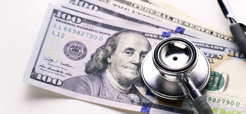 Stethoscope on a stack of hundred dollar bills.