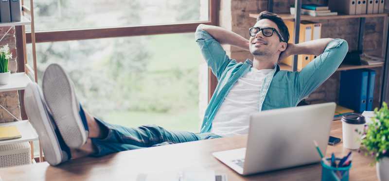 Man relaxing with feet up on desk and hands behind head.