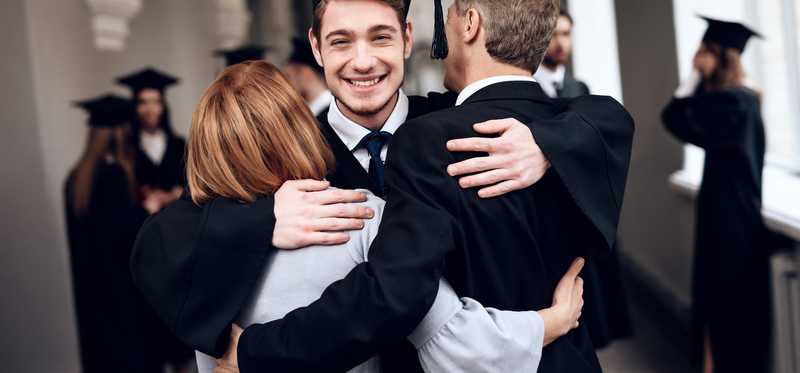 Parents hugging their graduate son.