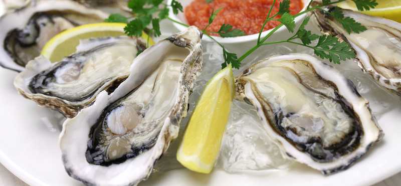 A plate of oysters and lemon wedges.