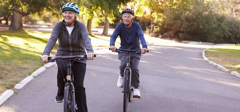 Elderly couple riding bikes together.