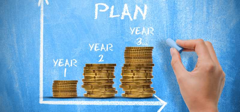 Words Retirement Plan on blue background with piles of coins.