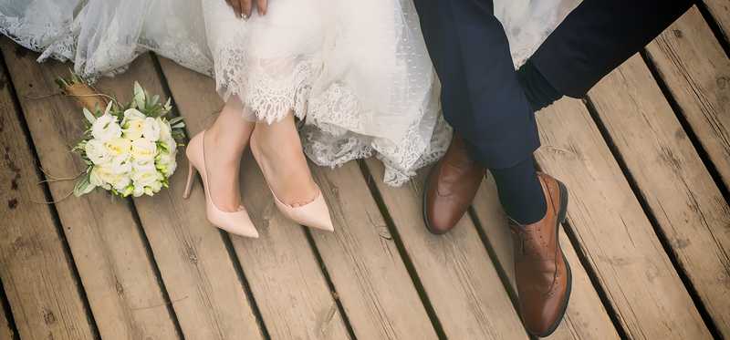 A bride and groom's feet together on a deck.