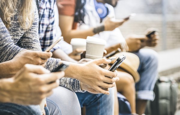 Group of people holding cups of coffee and using their cell phones.