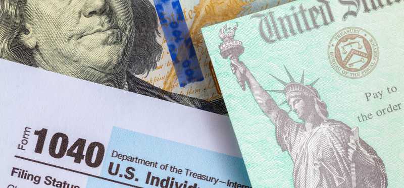 1040 tax form with refund check and hundred dollar bill.