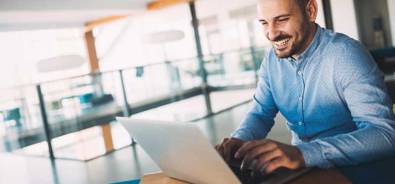 Smiling adult man using his laptop.