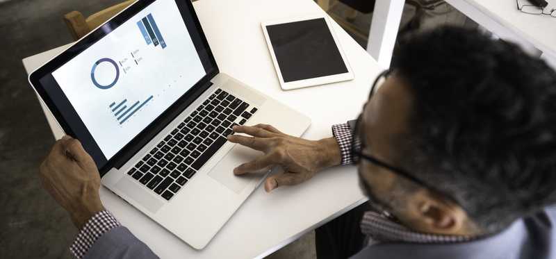 Overhead look at man working on his laptop at small desk