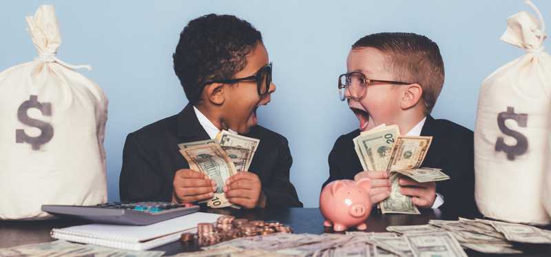 Two gleeful young people sitting with lots of cash in hand and bags of it next to them.