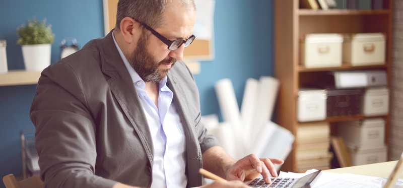 Person using calculator at desk in office.