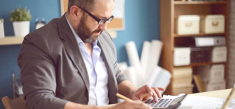 Person using calculator at desk in office.