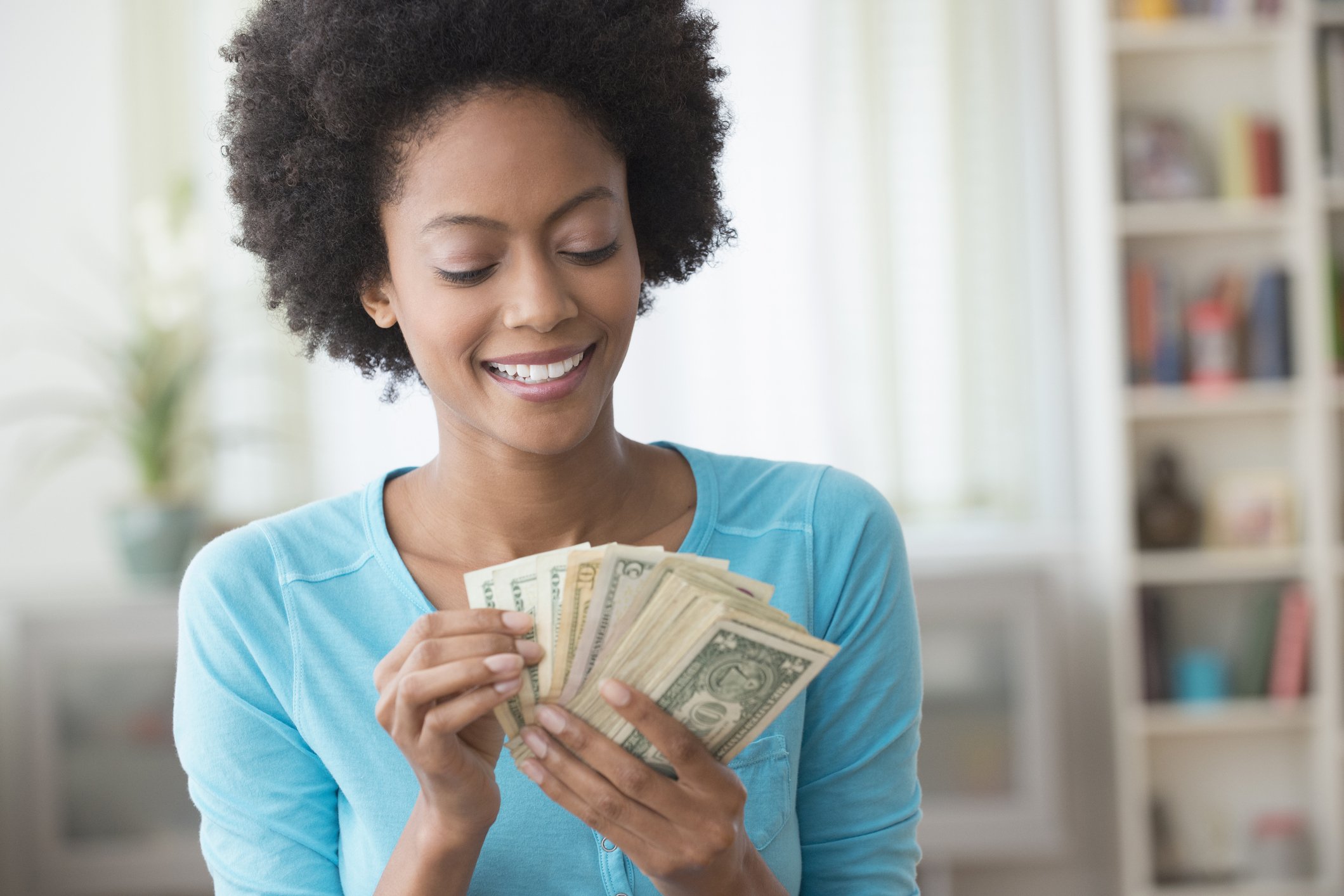 Smiling adult holds dollar bills in hand, fanned out.