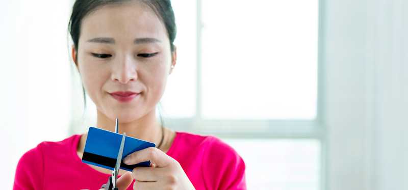 Person cutting credit card with scissors.