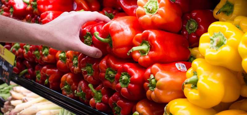 A hand reaches out and grabs produce.
