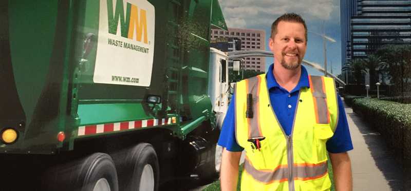 Waste Management employee stands by a garbage truck.