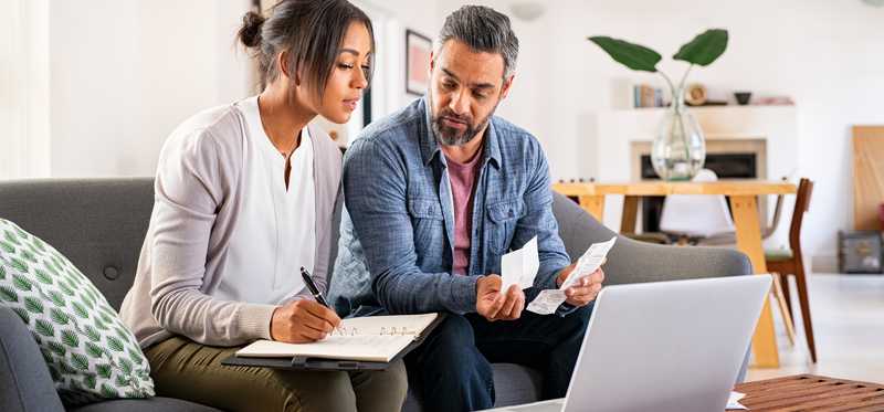 Two people sitting in front of a computer and reviewing paperwork.