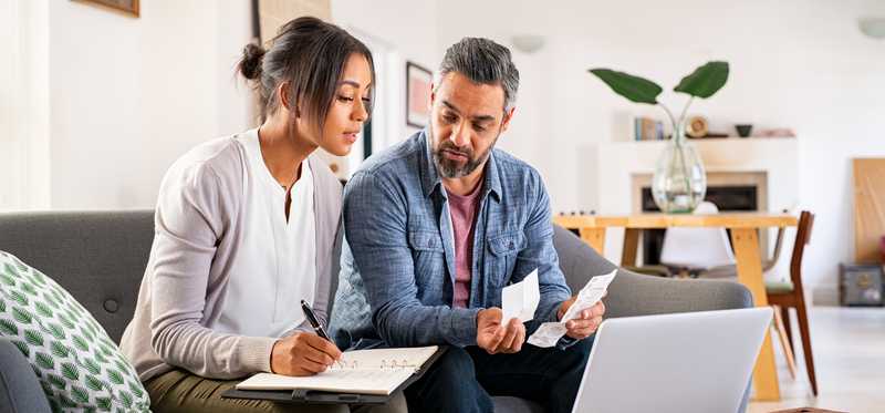 Two people sitting in front of a computer and reviewing paperwork.