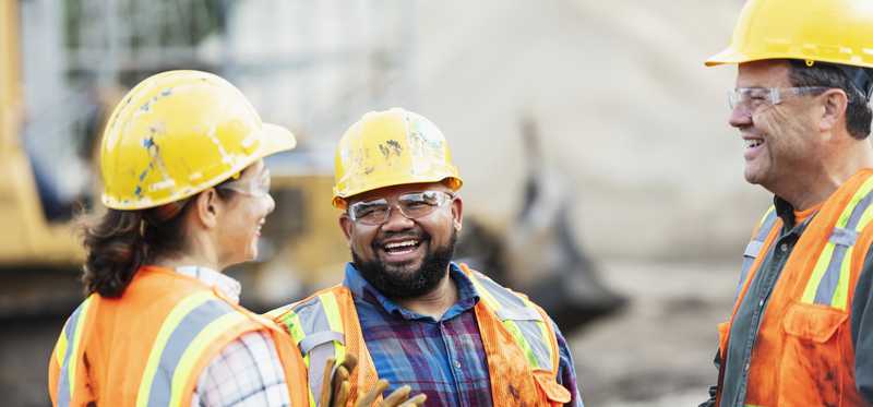 Three construction workers talking at a construction site.
