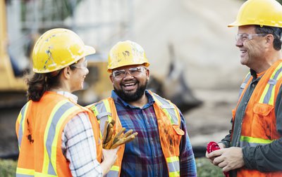 Three construction workers talking at a construction site.