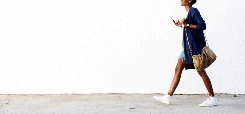 Woman walking with smartphone and earbuds