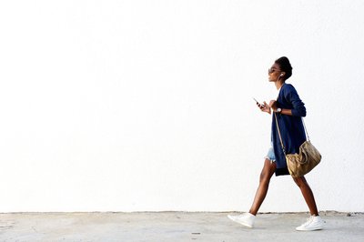 Woman walking with smartphone and earbuds