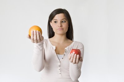 Woman holding apple in one hand and orange in other