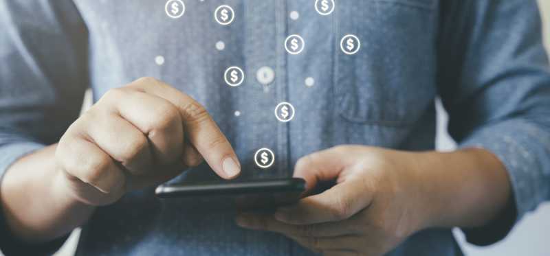 Man making online payment with dollar signs floating out of smartphone