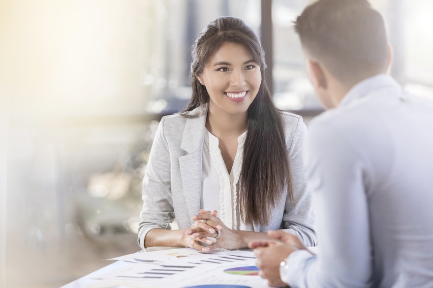 People meeting in an office with charts on table in front of them.