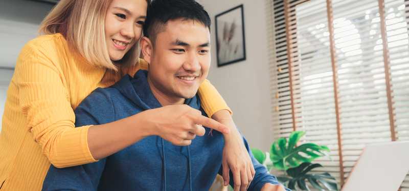 Two people smile while reviewing laptop screen together.