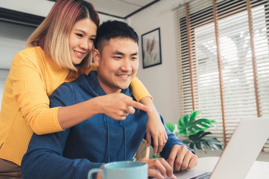 Two people smile while reviewing laptop screen together.