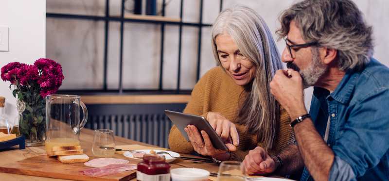 Two people looking at tablet during breakfast.