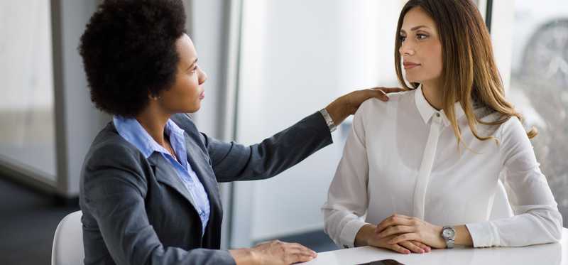 A person touches another person's shoulder during serious meeting in office.