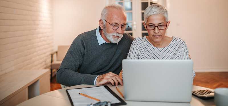 Older couple looking intently at a laptop screen.