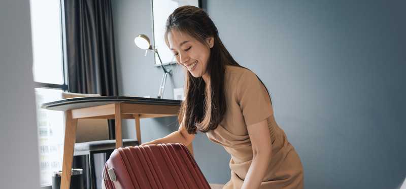 A person with a suitcase in an Airbnb-type room.