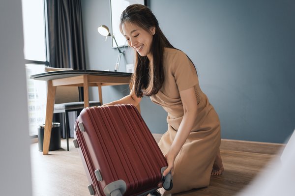 A person with a suitcase in an Airbnb-type room.