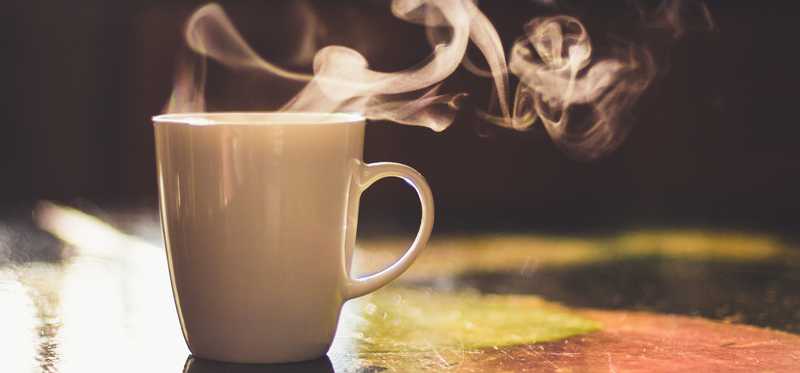 Steaming coffee cup sitting on a counter surface