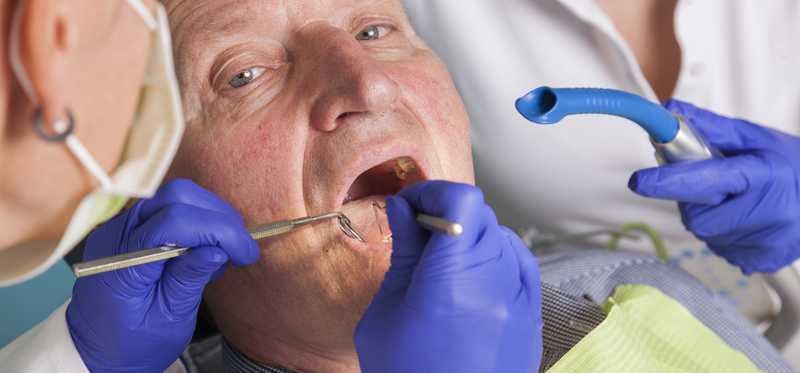 Dentist giving elderly man a dental exam