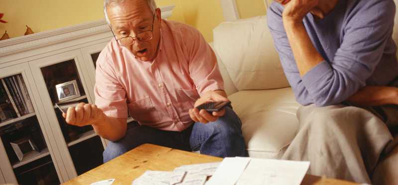 We see an unhappy middle-aged couple going over their finances, looking at papers.