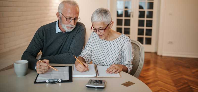 Two people writing in notebooks together.