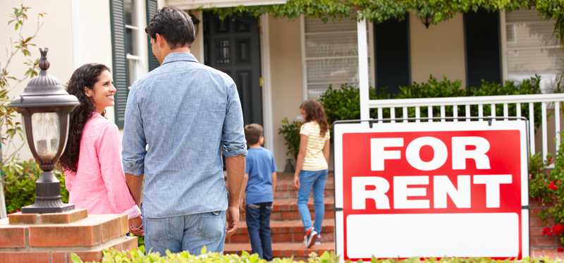 People walking toward home that has For Rent sign out front