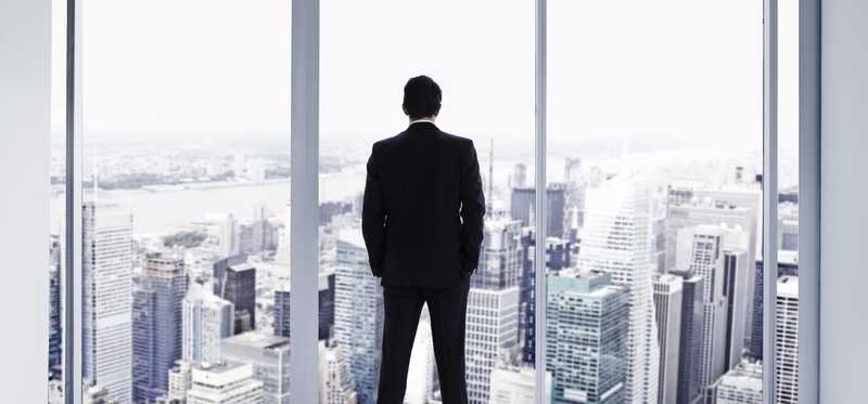 Man standing in window looking over city
