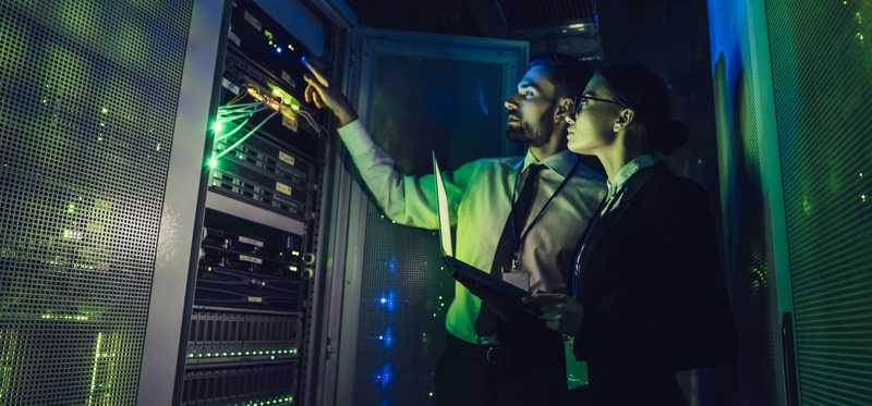 Two people looking at computer server.